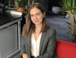 Person in grey blazer and white blouse sitting on a sofa in an office