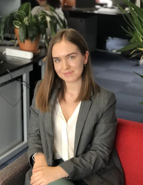 Person in grey blazer and white blouse sitting on a sofa in an office