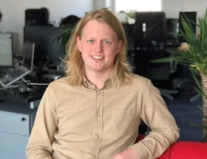 Person in beige shirt sitting on a sofa in an office
