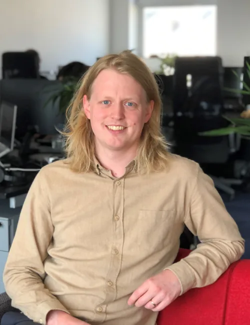 Person in beige shirt sitting on a sofa in an office