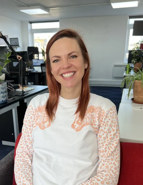 Person in white sweatshirt sitting on a sofa in an office