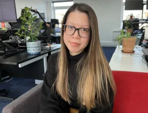 Person in black sweater sitting on a sofa in an office