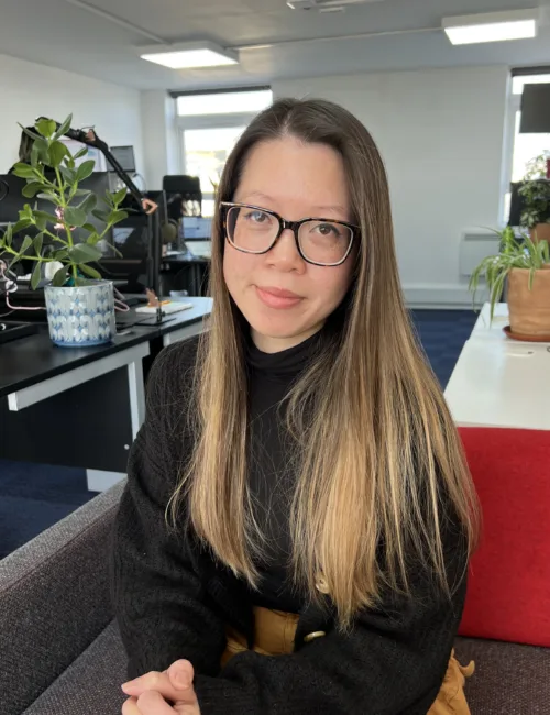 Person in black sweater sitting on a sofa in an office