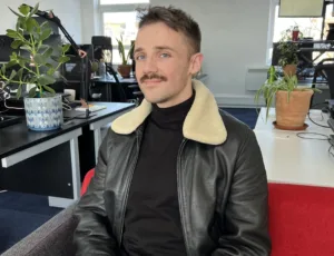 Person in black leather jacket sitting on a sofa in an office