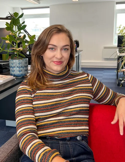 Person in stripped sweater sitting on a sofa in an office