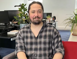 Person in checked shirt sitting on a sofa in an office