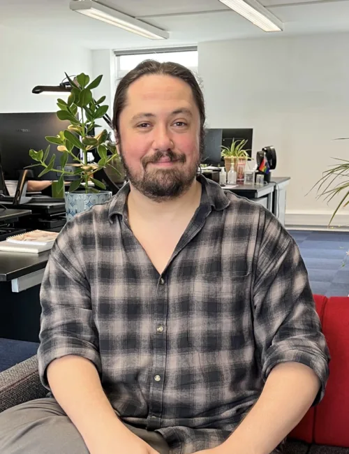 Person in checked shirt sitting on a sofa in an office