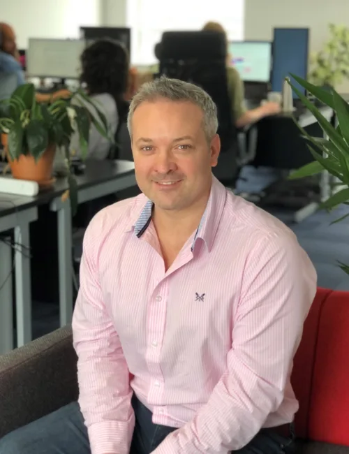 Person in pink shirt sitting on a sofa in an office