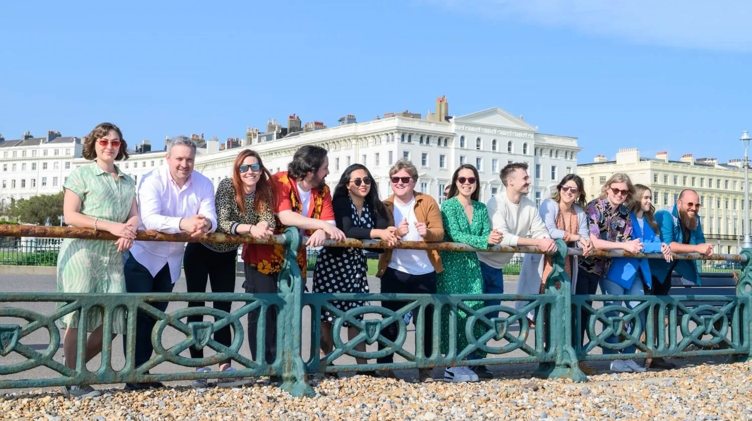 people leaning on beach handrail in hove