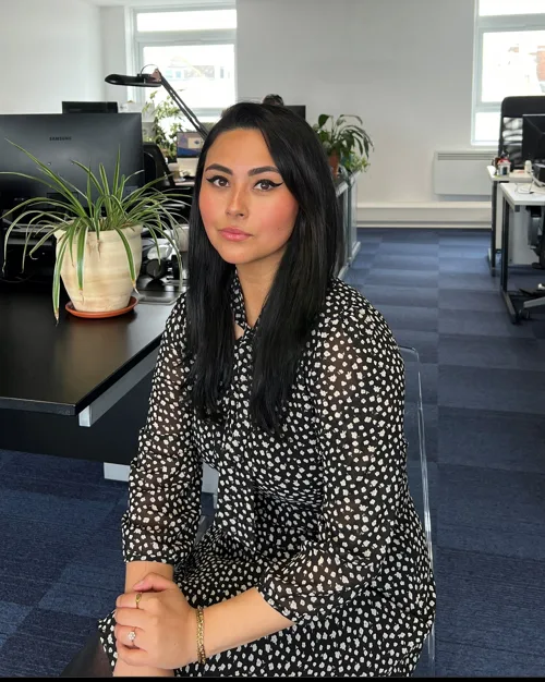 Woman in black and white floral printed dress sat in an office.